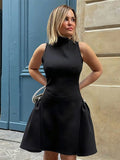 Woman wearing a black dress standing against a stone wall and blue door.