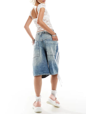 Person wearing a white sleeveless top and denim shorts on a white background