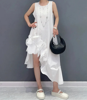 Woman wearing a white dress with ruffles against a gray background