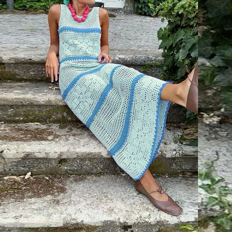Person sitting on steps wearing a long, light blue and white crocheted dress.