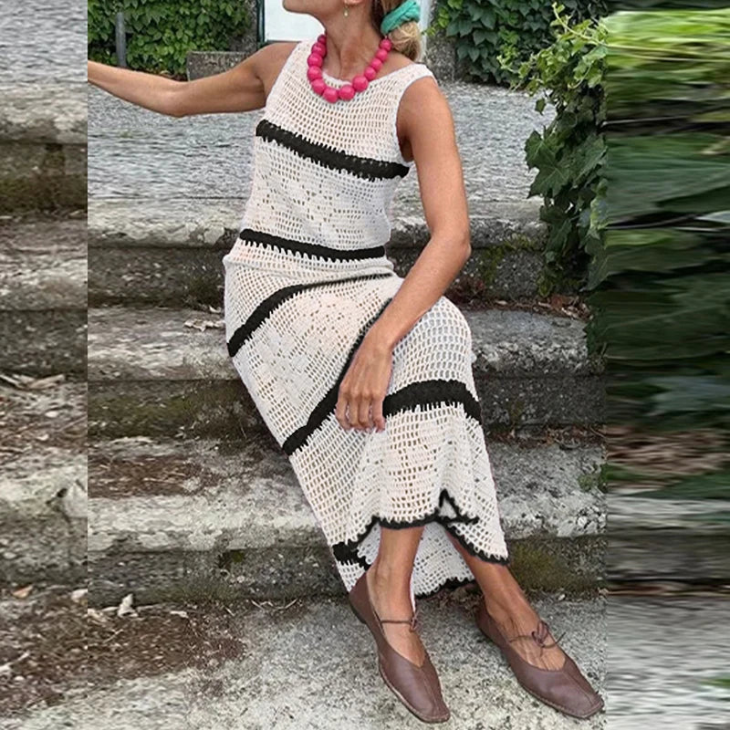 Woman wearing a white and black striped dress sitting on stone steps.