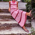 Person wearing a pink and red striped dress sitting on wooden steps.