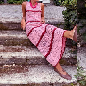 Person wearing a pink and red striped dress sitting on wooden steps.