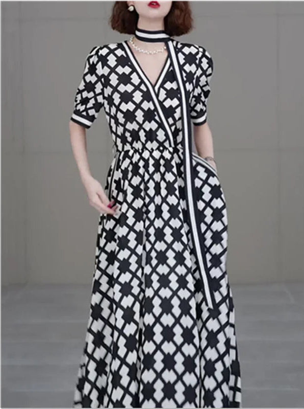Woman wearing a black and white patterned dress against a plain background