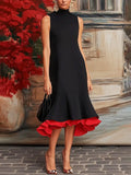 Woman wearing a black dress with a red hem in front of a decorative wall.