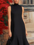 Woman wearing a black sleeveless dress with a textured wall in the background