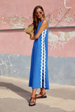 Woman wearing a blue dress with white stripes against a pink and gray wall.