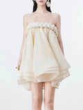 Woman wearing a strapless beige dress with floral details on a white background