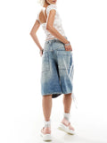 Person wearing a white sleeveless top and denim shorts on a white background