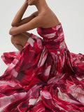 Woman wearing a red and white floral dress against a plain background