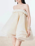 Woman wearing a strapless beige dress with floral details on a white background