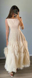 Woman taking a mirror selfie wearing a long, flowing dress with feather details.