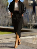 Person wearing a black outfit with a white top and tan boots in an urban setting.