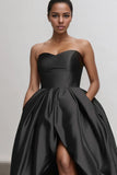 Woman wearing a black strapless gown against a plain background
